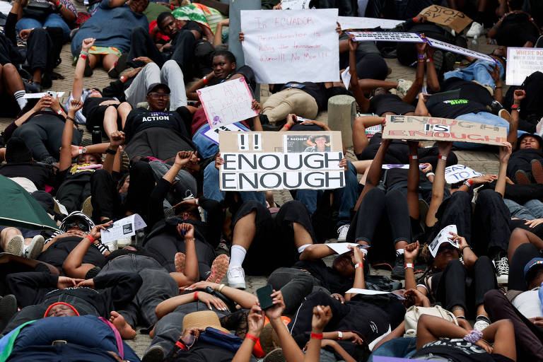 Grupo de mulheres deitadas no chão em protesto simbólico durante o Women